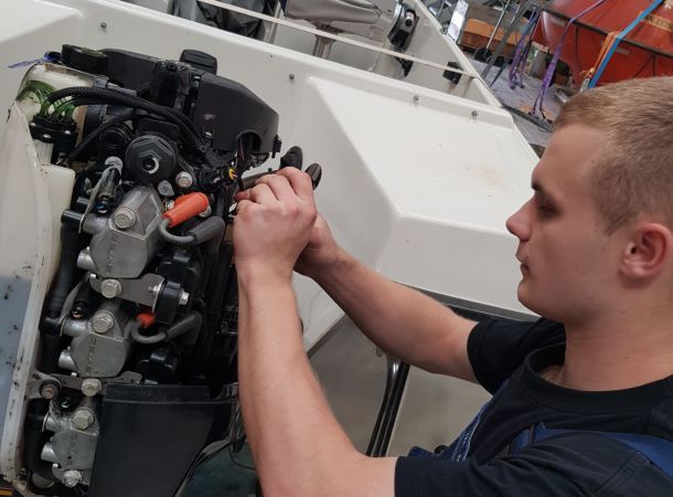 Tekniker justerer en Yamaha påhængsmotors motorblok under service