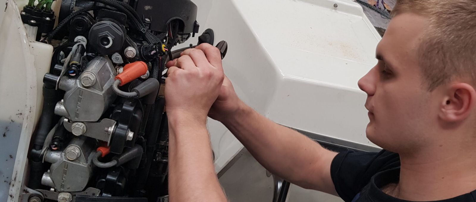 Tekniker justerer en Yamaha påhængsmotors motorblok under service